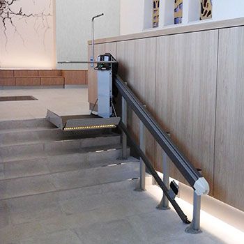 a set of stairs leading up to a wall with pictures on it and an empty bench at the bottom