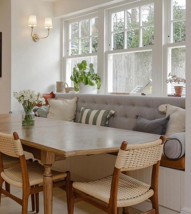 a living room filled with furniture next to a window covered in white curtains and pillows