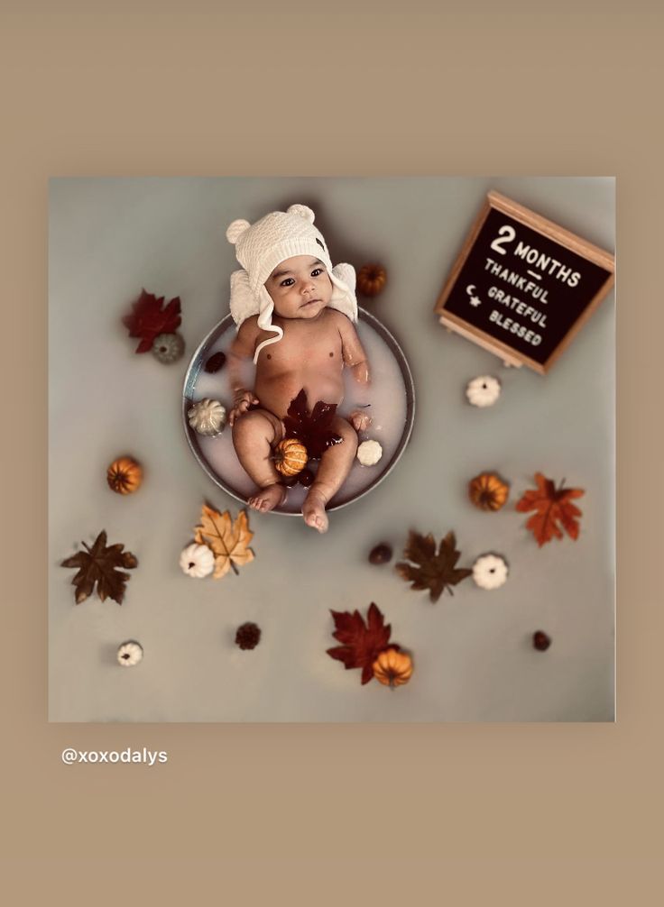 there is a cake with a baby on it and autumn leaves around the cake, including acorns