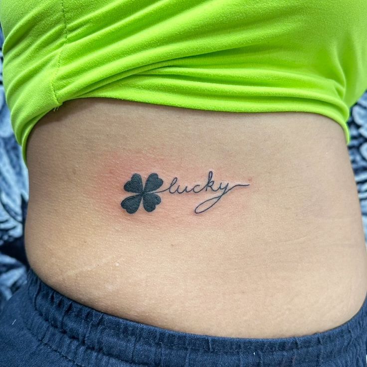 a woman's stomach with the word lucky tattooed on it