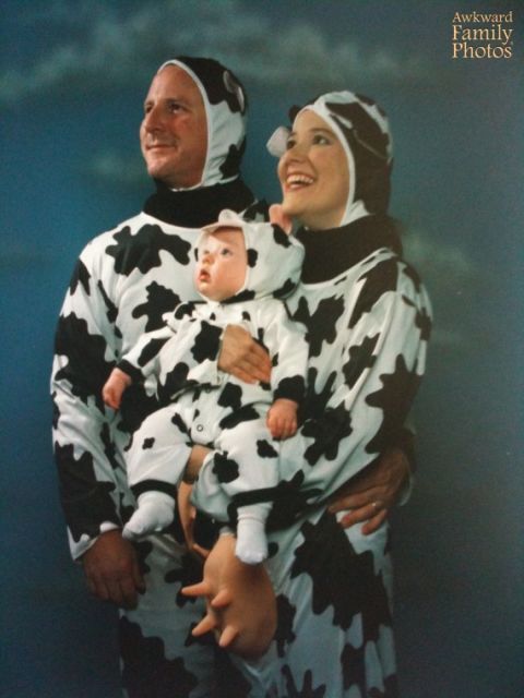 a man and woman holding a baby dressed in cow print clothes, both wearing head coverings