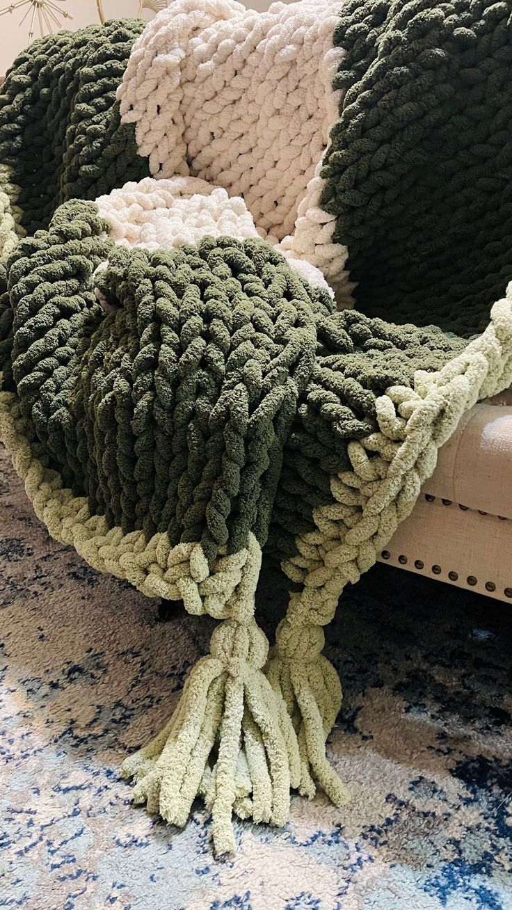 a pile of knitted pillows sitting on top of a rug next to a couch