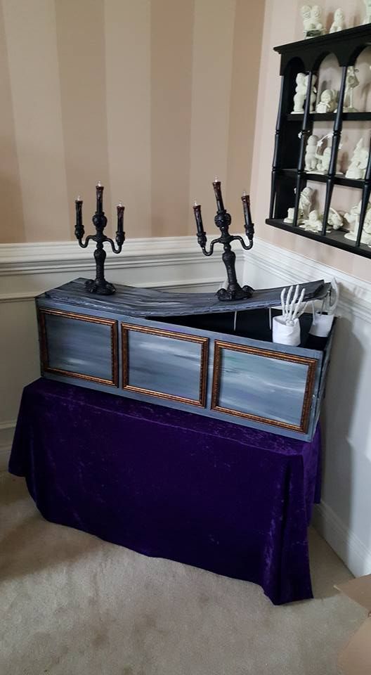 a purple table with candles on it in front of a mirror and wall mounted shelf