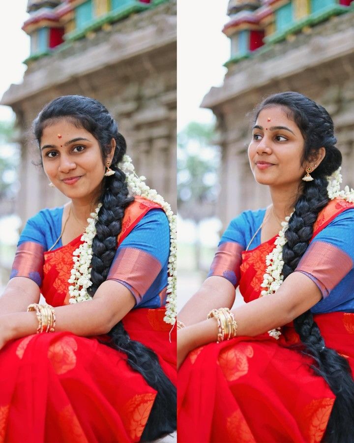 a woman sitting on the ground wearing a red and blue sari with flowers in her hair