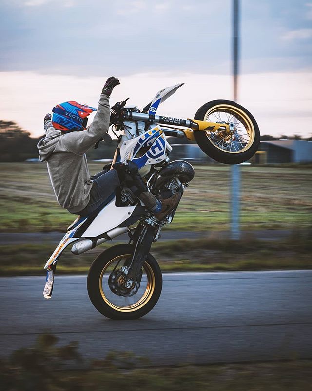 a person on a motorcycle doing a wheelie in the air with his hands up