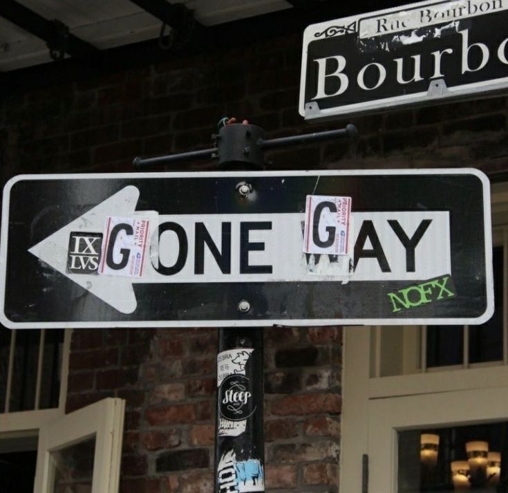 a street sign that says bourbon and one gay on the side of a brick building