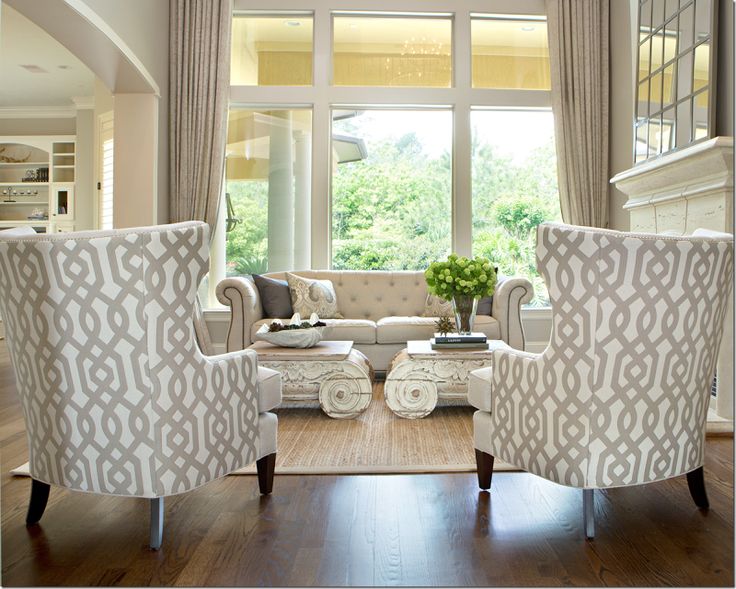 a living room filled with furniture next to a large window covered in white drapes