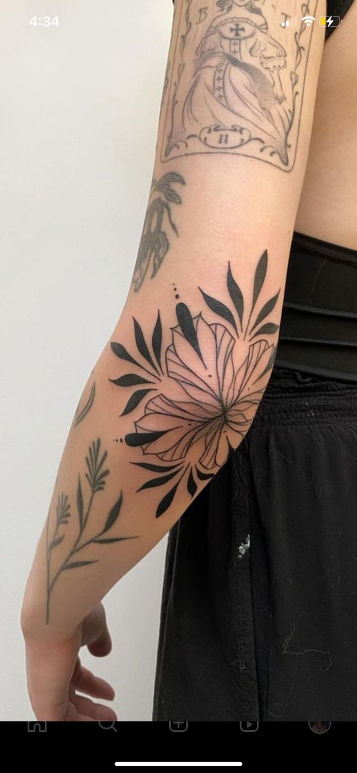 a woman's arm with tattoos on it, and flowers in the middle of her arm