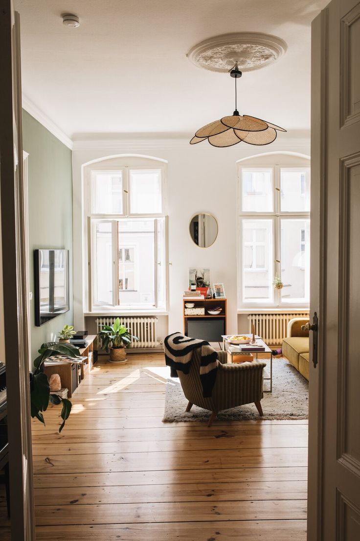 an open door leading to a living room filled with furniture and plants on the floor