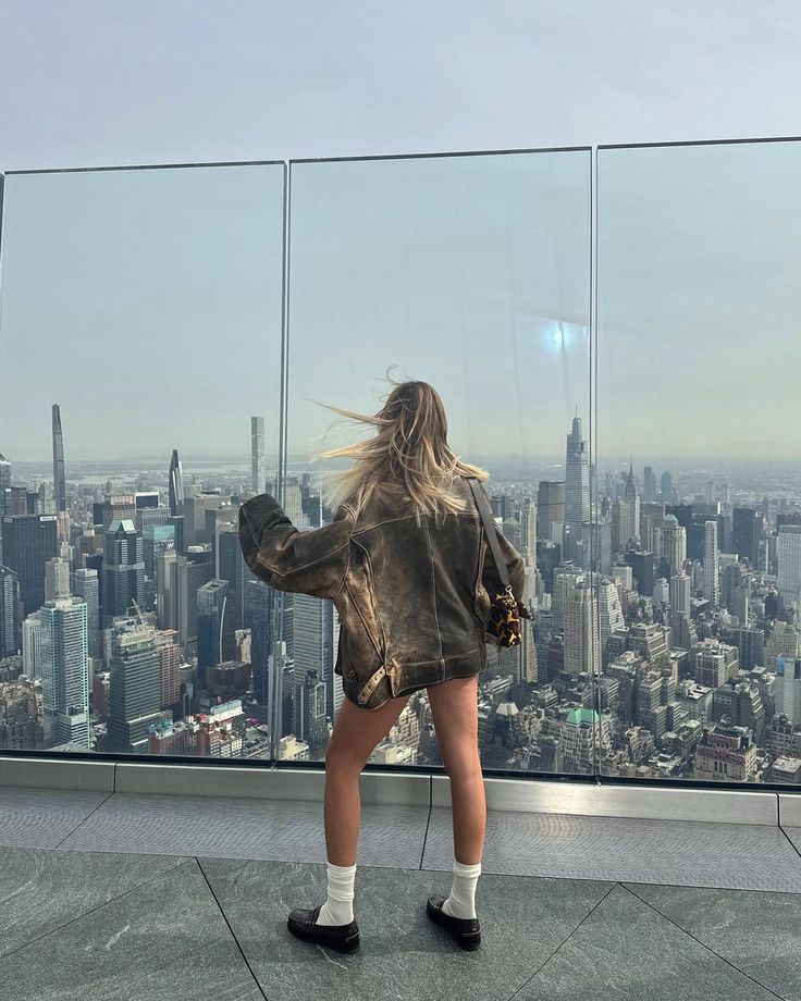 a woman standing on top of a building looking out at the city from an observation platform