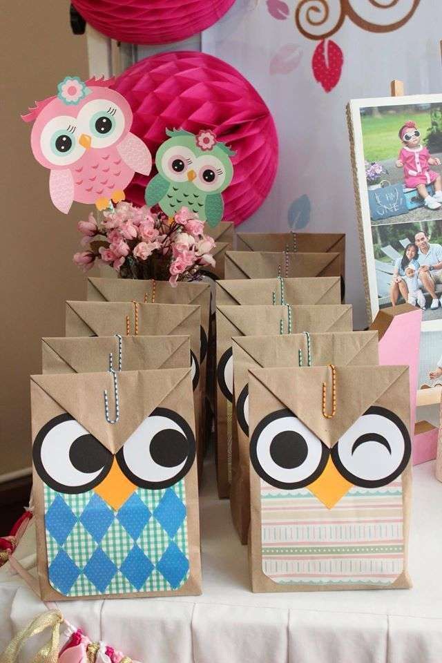 an owl themed birthday party with pink decorations and paper bags on the table for guests