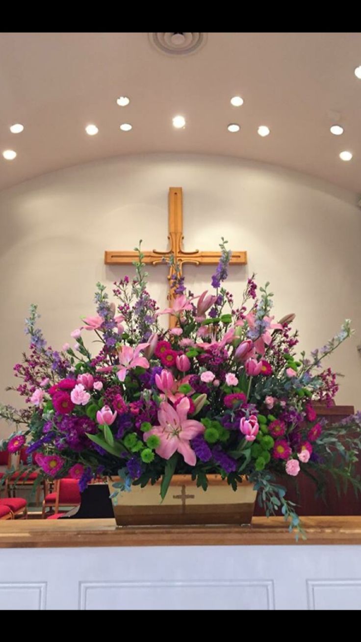 a cross with flowers on the altar in a church