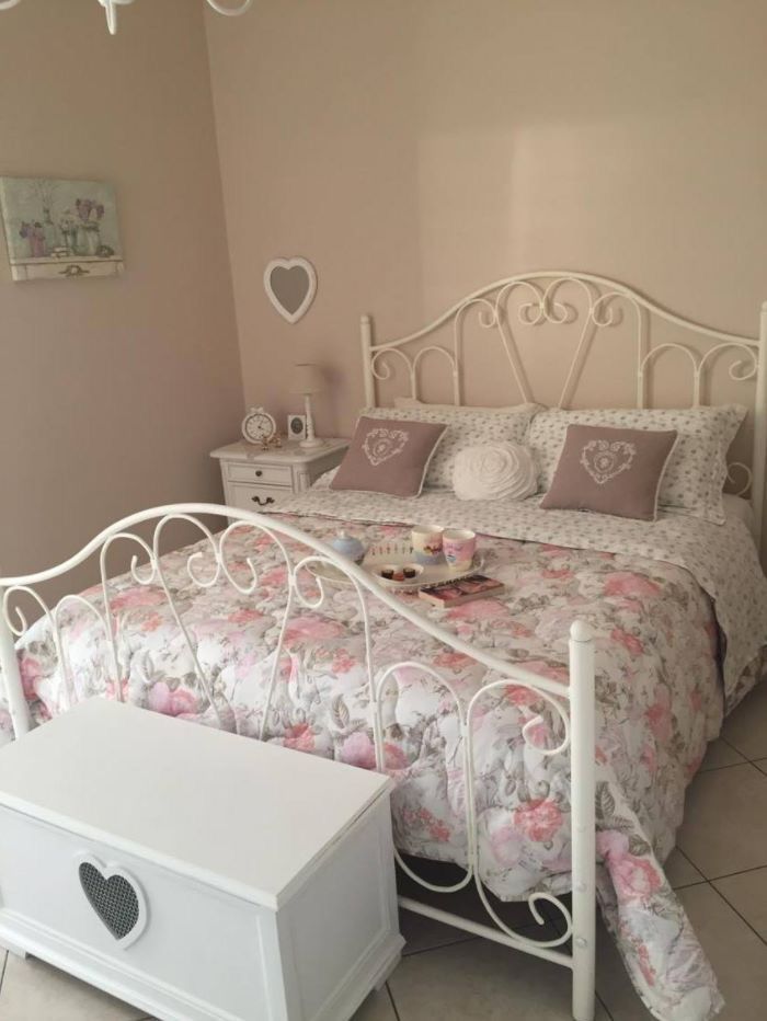 a white bed sitting in a bedroom on top of a tiled floor next to a dresser