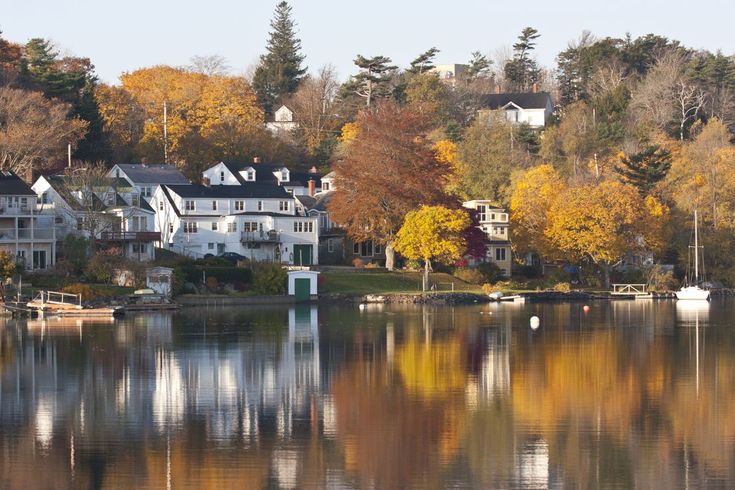 houses on the shore of a lake surrounded by autumn foliage and trees with yellow leaves