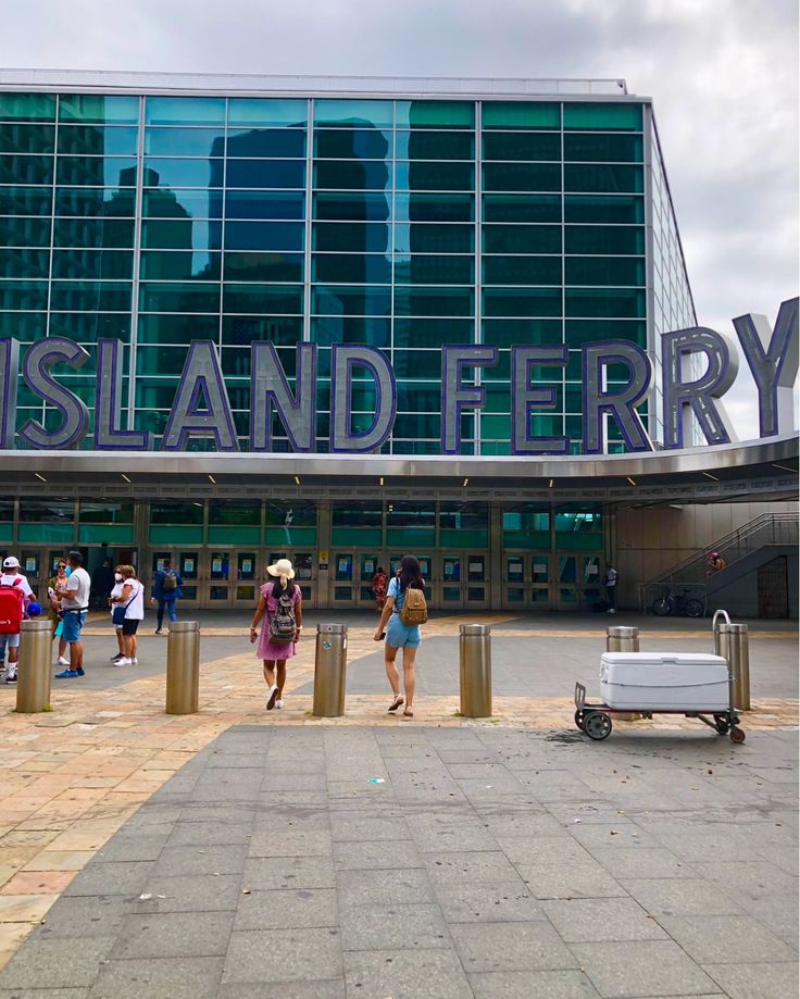 people walking in front of the entrance to a large building with a sign that says island ferry