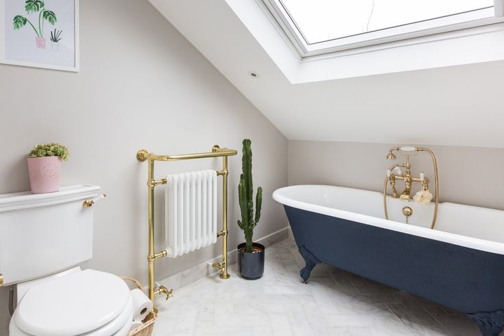 a white and blue bathroom with a skylight above the bathtub, toilet and radiator