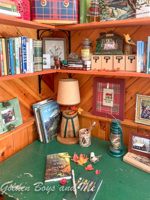 a green table topped with lots of books next to a shelf filled with pictures and other items