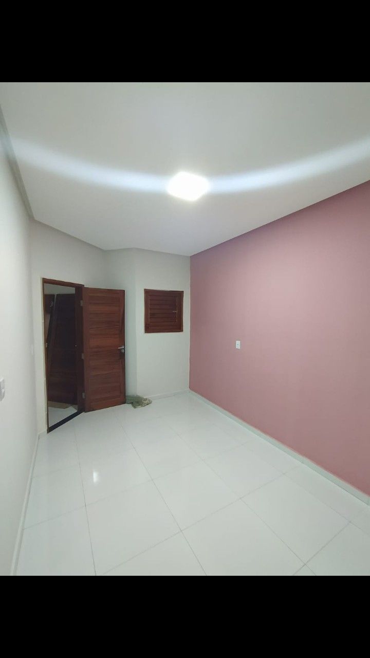 an empty room with pink walls and white flooring is pictured in this image, there are two doors on the far wall