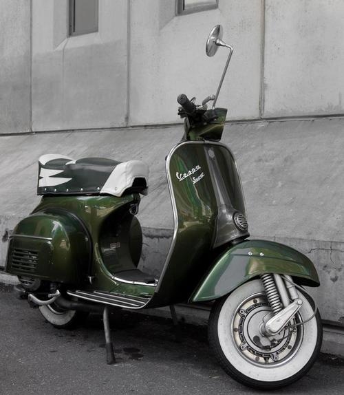 a green scooter parked next to a building