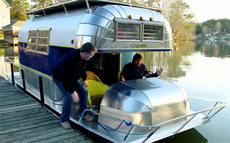 two men are standing on the dock next to a boat that is floating in water