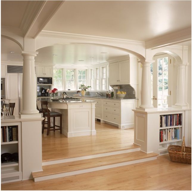 an open floor plan with white cabinets and wood floors