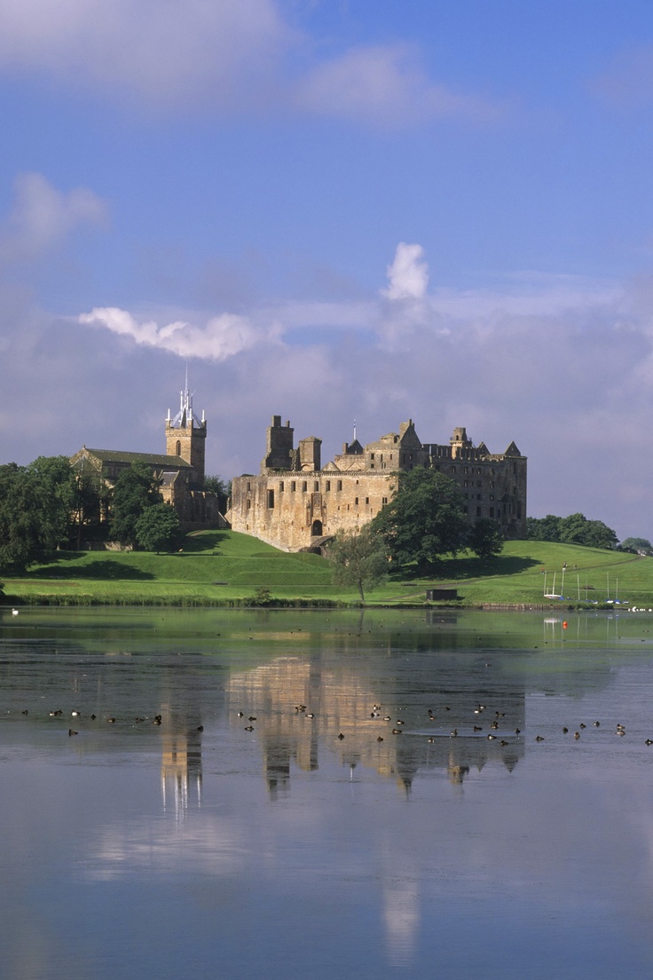 a castle sitting on top of a lush green hillside