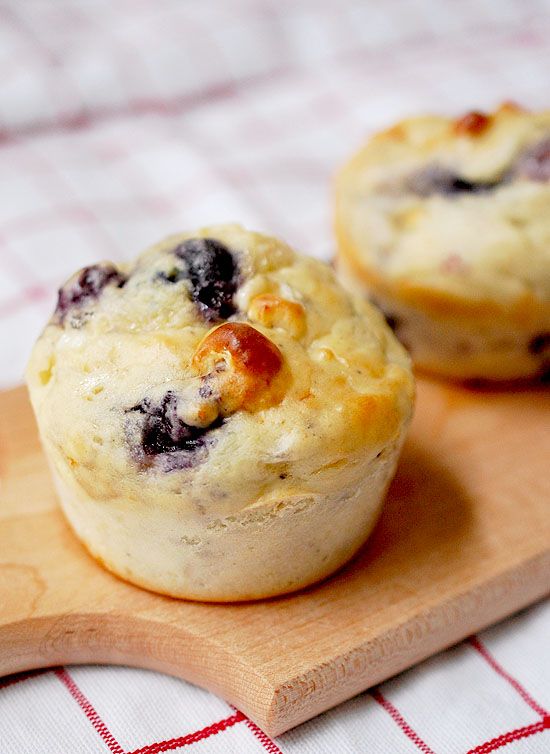 two blueberry muffins sitting on top of a wooden cutting board