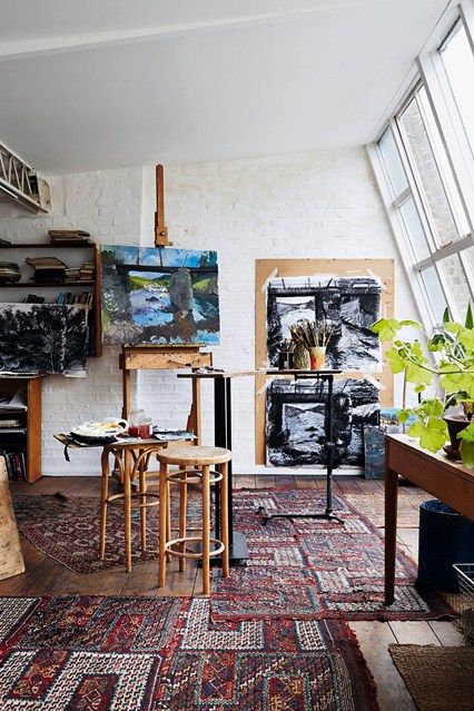 an artist's studio with paintings, stools and plants in the foreground