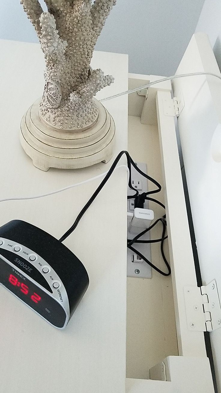 an alarm clock sitting on top of a white table next to a vase filled with flowers