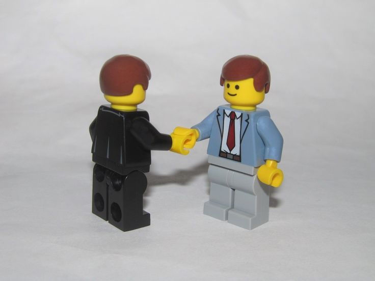 two lego figures are holding hands on a white background with one is wearing a suit and the other has a red tie