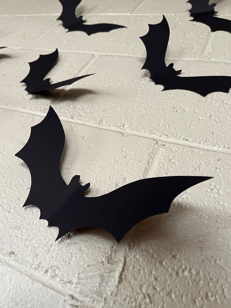 several black bats are flying in the air on a white tile floor, and one is upside down