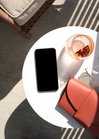 a cell phone sitting on top of a white table next to a drink and purse