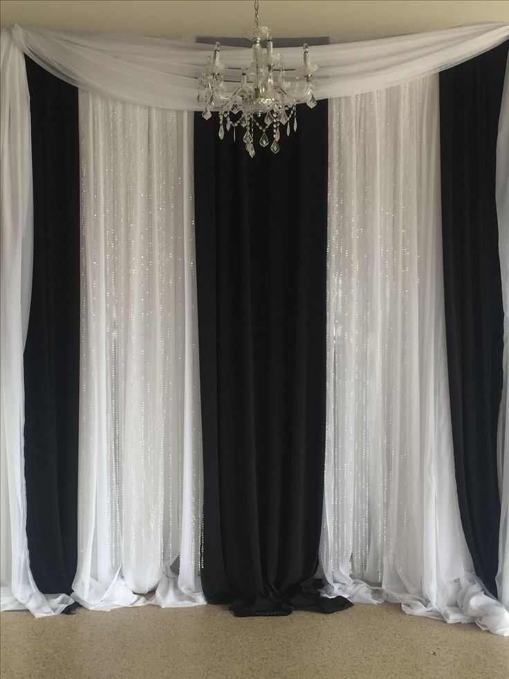 a chandelier hanging from the ceiling in front of black and white drapes