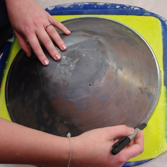 a woman is using a metal bowl to hold something in her hand while sitting on a yellow and blue tray