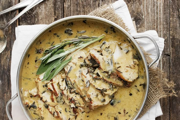 a pan filled with chicken and mushrooms on top of a table next to a napkin