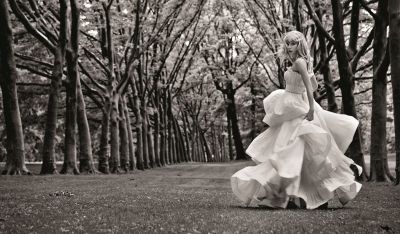 a woman in a dress is walking through the woods