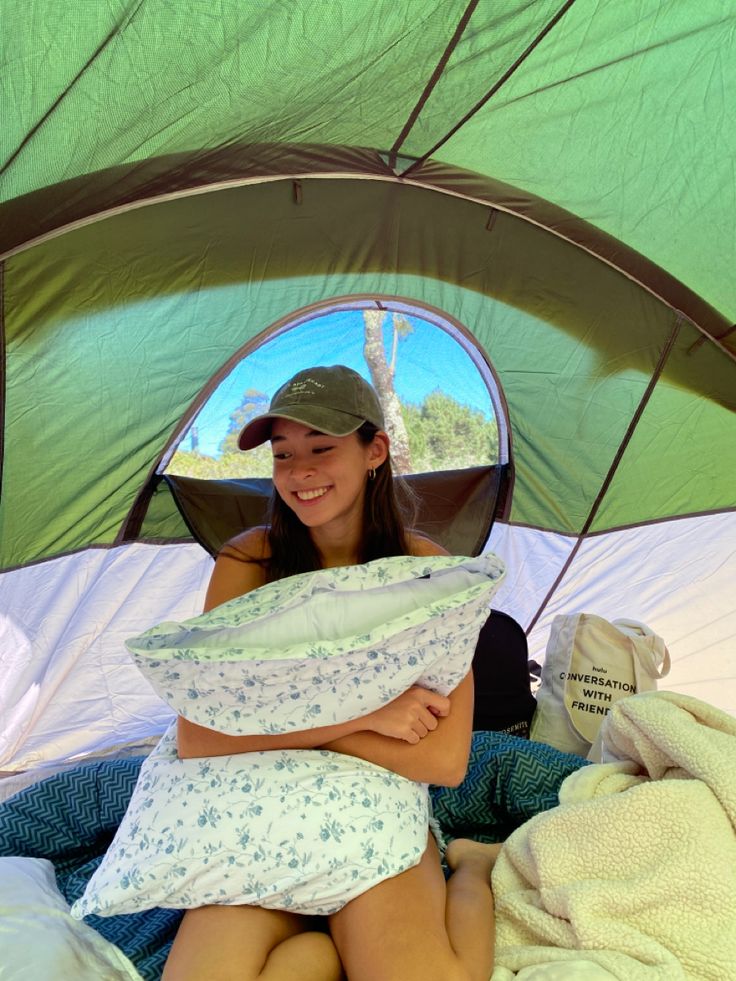 a woman sitting on top of a bed in a tent