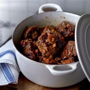 a pot filled with meat and carrots on top of a table