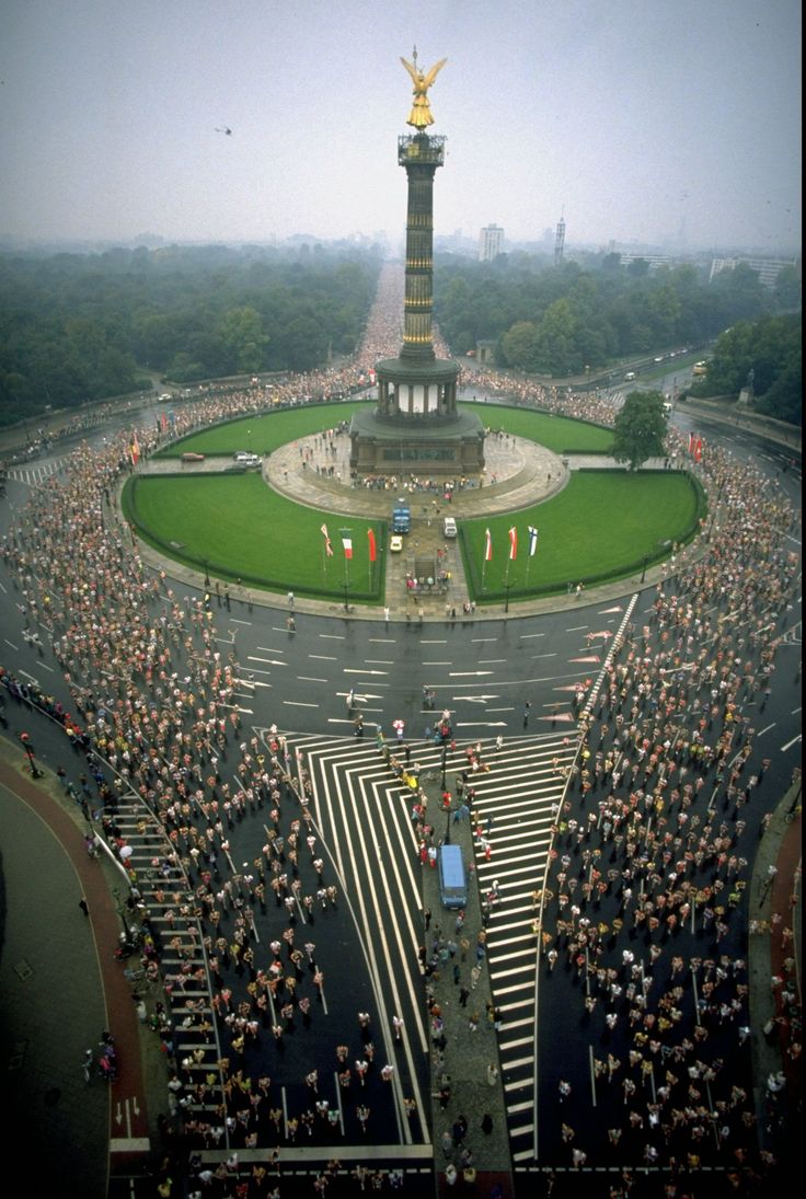 an aerial view of a large crowd gathered in front of a monument with a golden statue on top