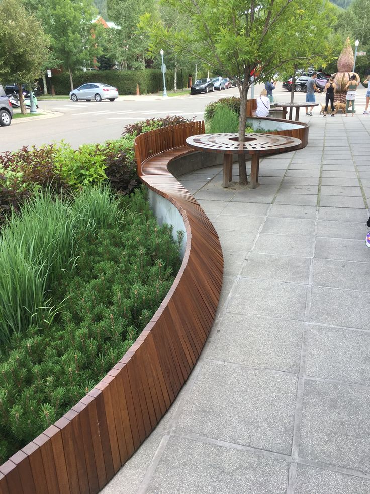 a wooden bench sitting next to a lush green park