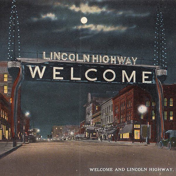 the welcome sign to lincoln highway is lit up in the night sky above an empty street