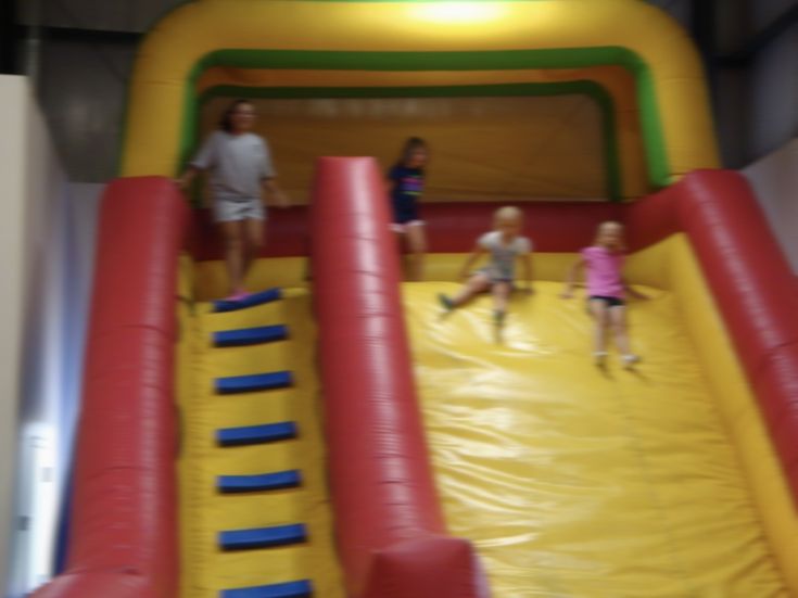 three children are playing on an inflatable slide