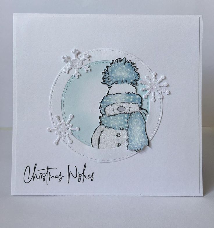 a white card with a blue teddy bear wearing a winter hat and holding a snowflake