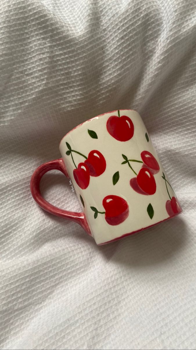 painted cherry mug on duvet Cherry Pottery Mug, Aesthetic Cup Painting, Cherries Pottery Painting, Mug Paint Designs, Cup Designs Painting, Diy Cup Painting, Painting On Cups Ideas, Cherry Mug Painting, Paint On Mugs Diy