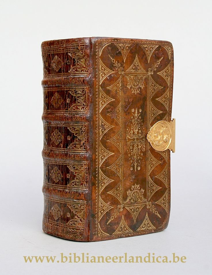 an old leather book with intricate designs on the front and back cover is open to reveal a gold medallion