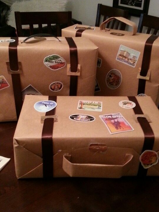 several brown suitcases with stickers on them sitting on a wooden table next to a chair