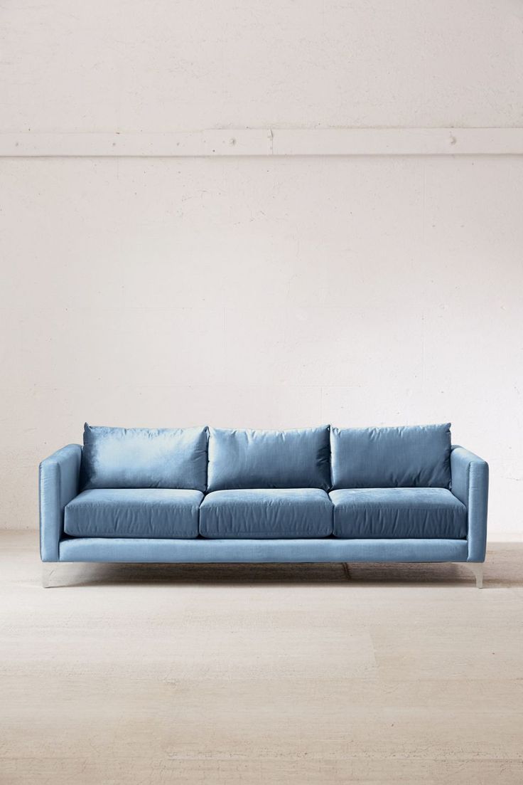 a blue couch sitting on top of a wooden floor next to a white wall in an empty room