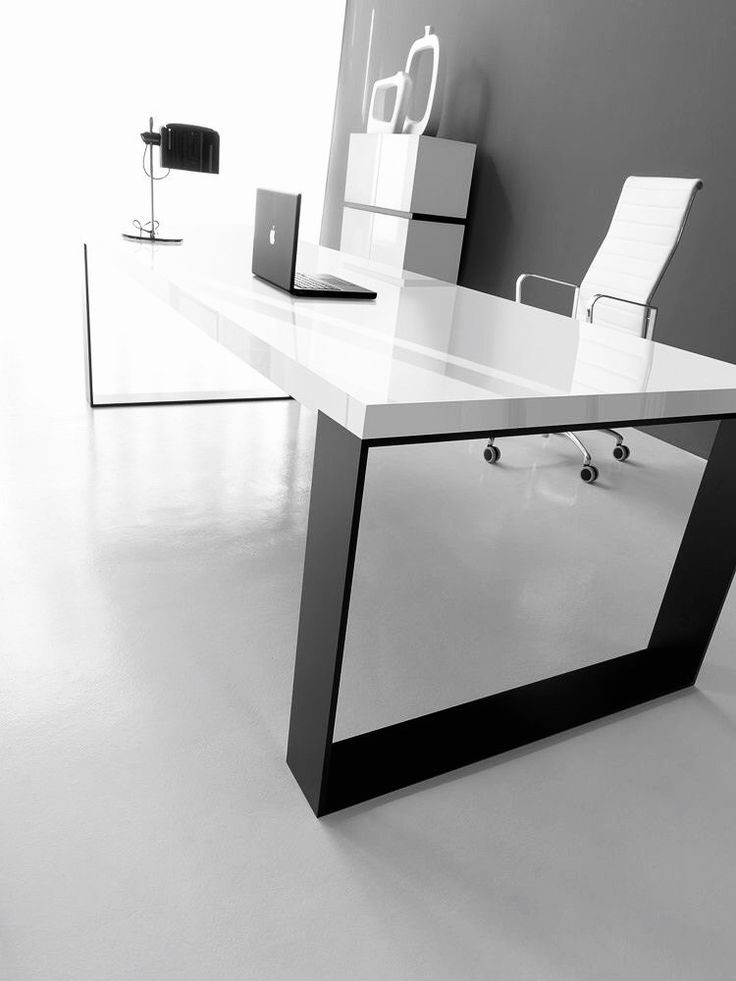 an office desk with a laptop on it in front of a white wall and chair