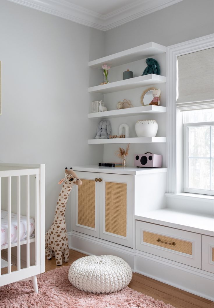 a baby's room with white shelves and pink rugs on the floor next to a crib