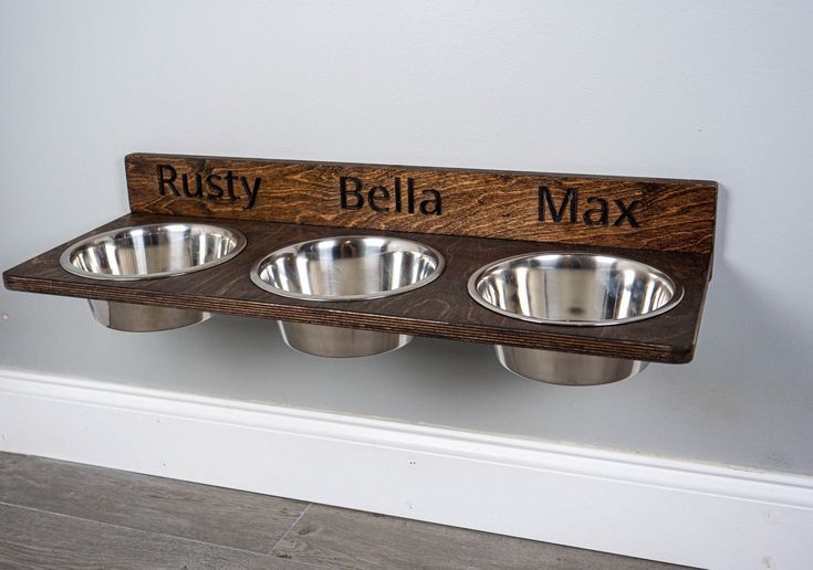 three stainless steel bowls are mounted on a wooden plaque that says, rusty bella max